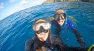 Two staff members in scuba diving gear taking a selfie in the water.