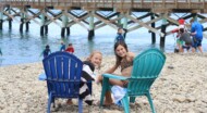 A camper sitting at a beach, posing with her thumbs up.